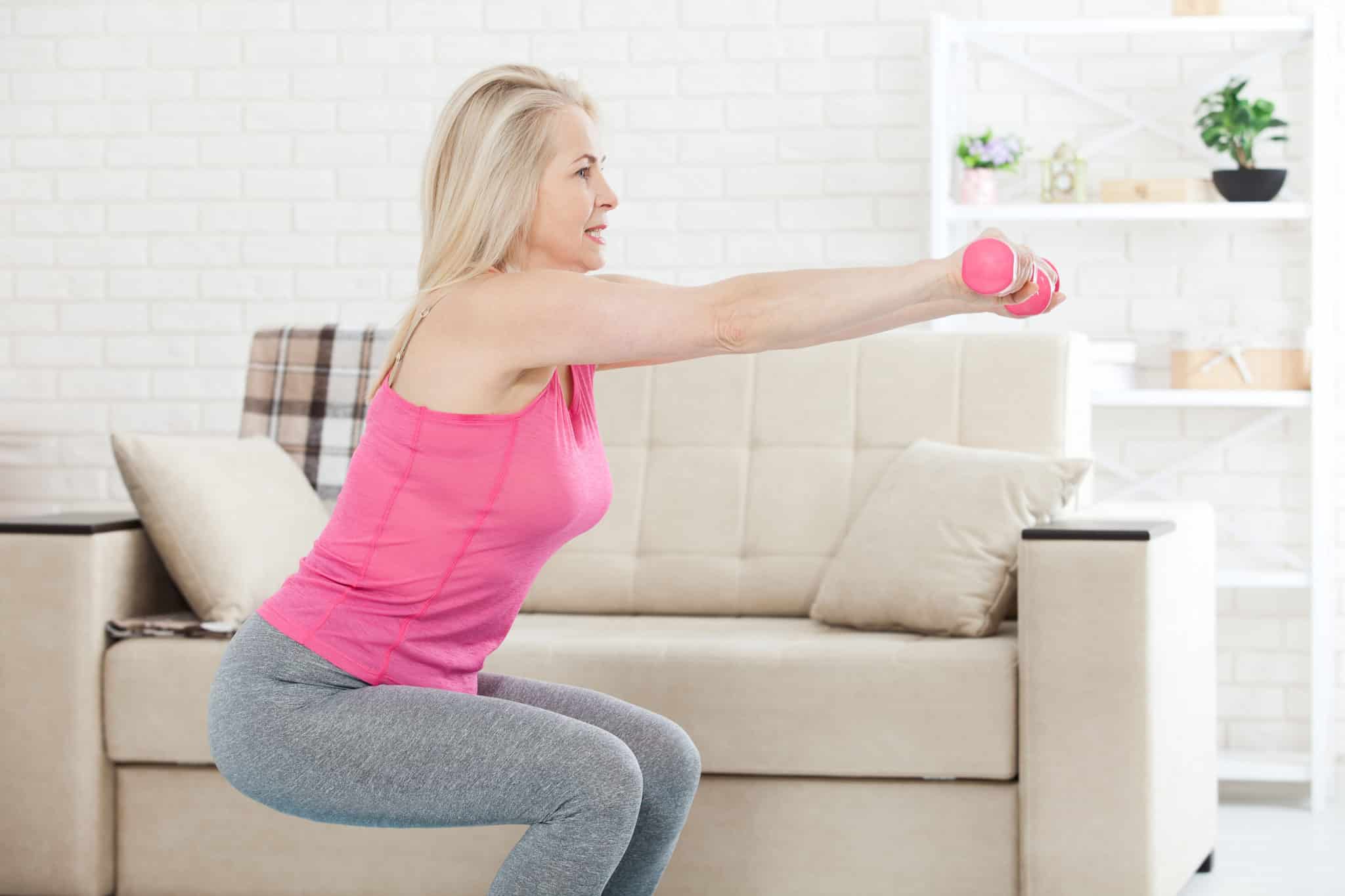 Woman implicit    50 holding dumbbells and squatting successful  surviving  country   for spot    grooming  session
