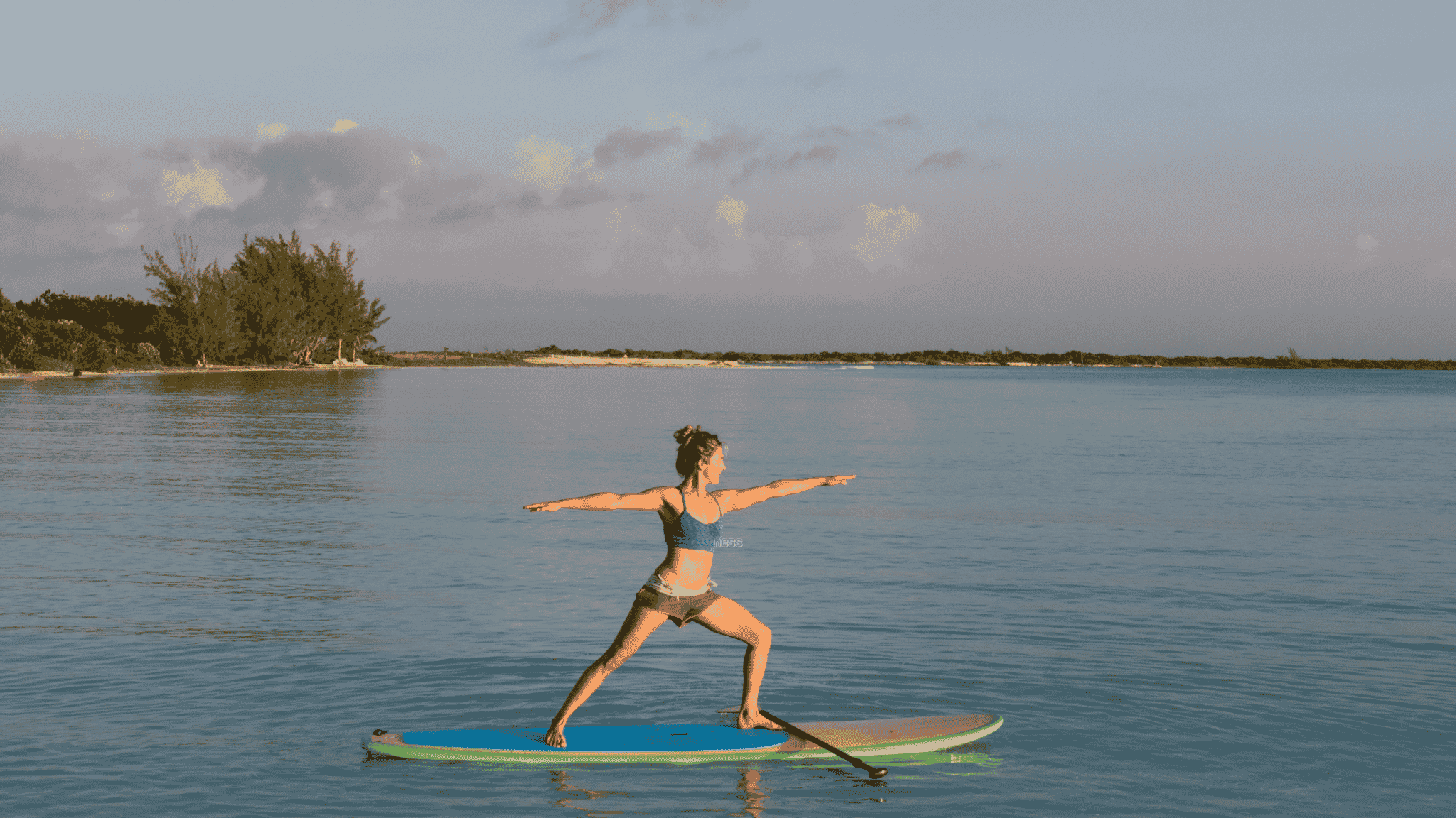 woman doing yoga on paddleboard at sunset