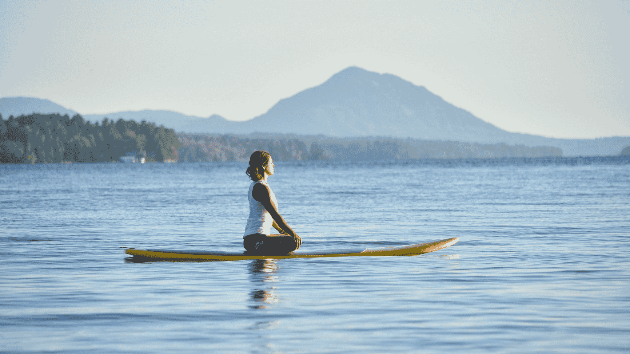 woman sitting on paddleboard in peaceful setting