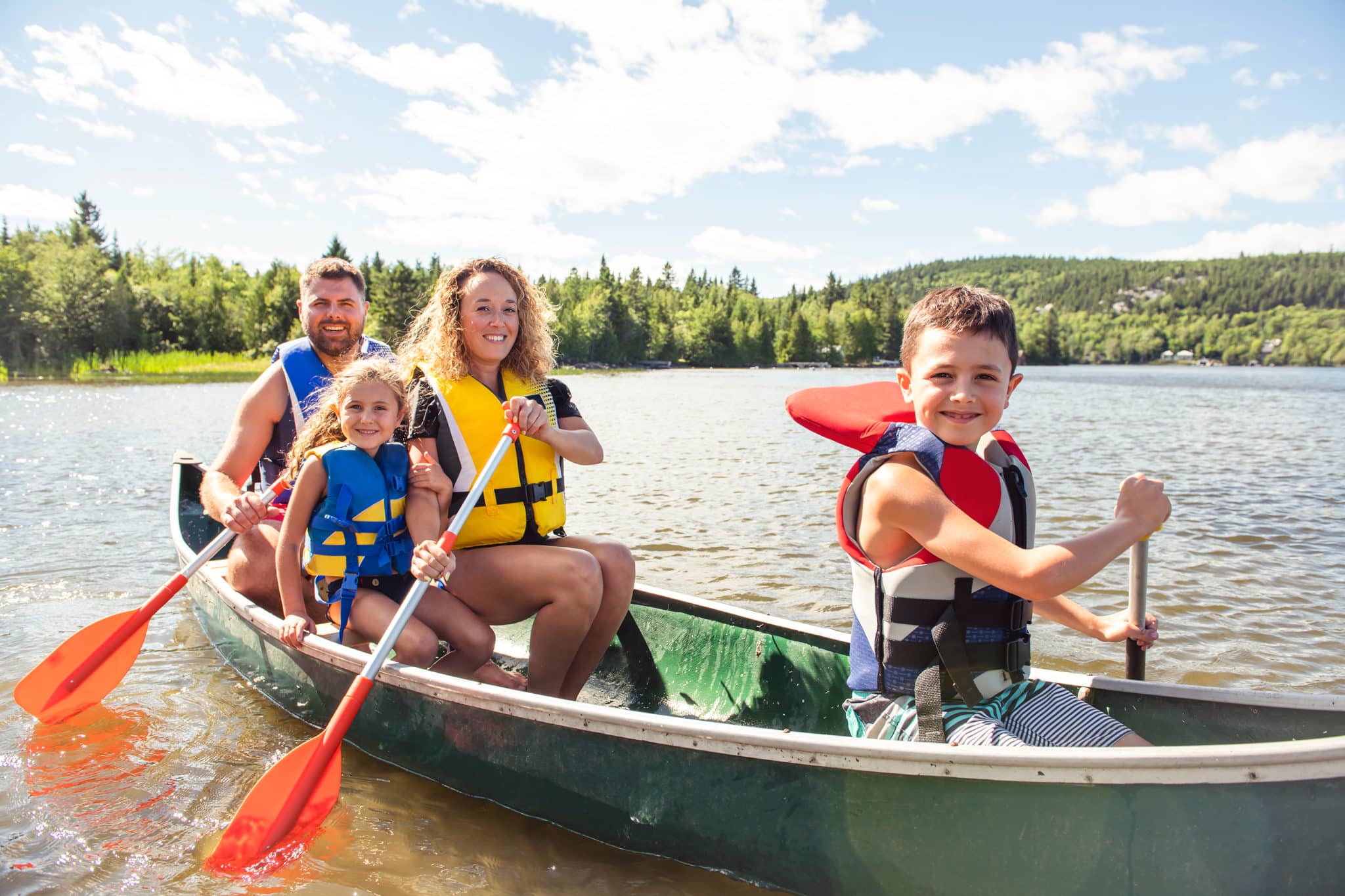 Family of four canoeing on lake for fun summer activity