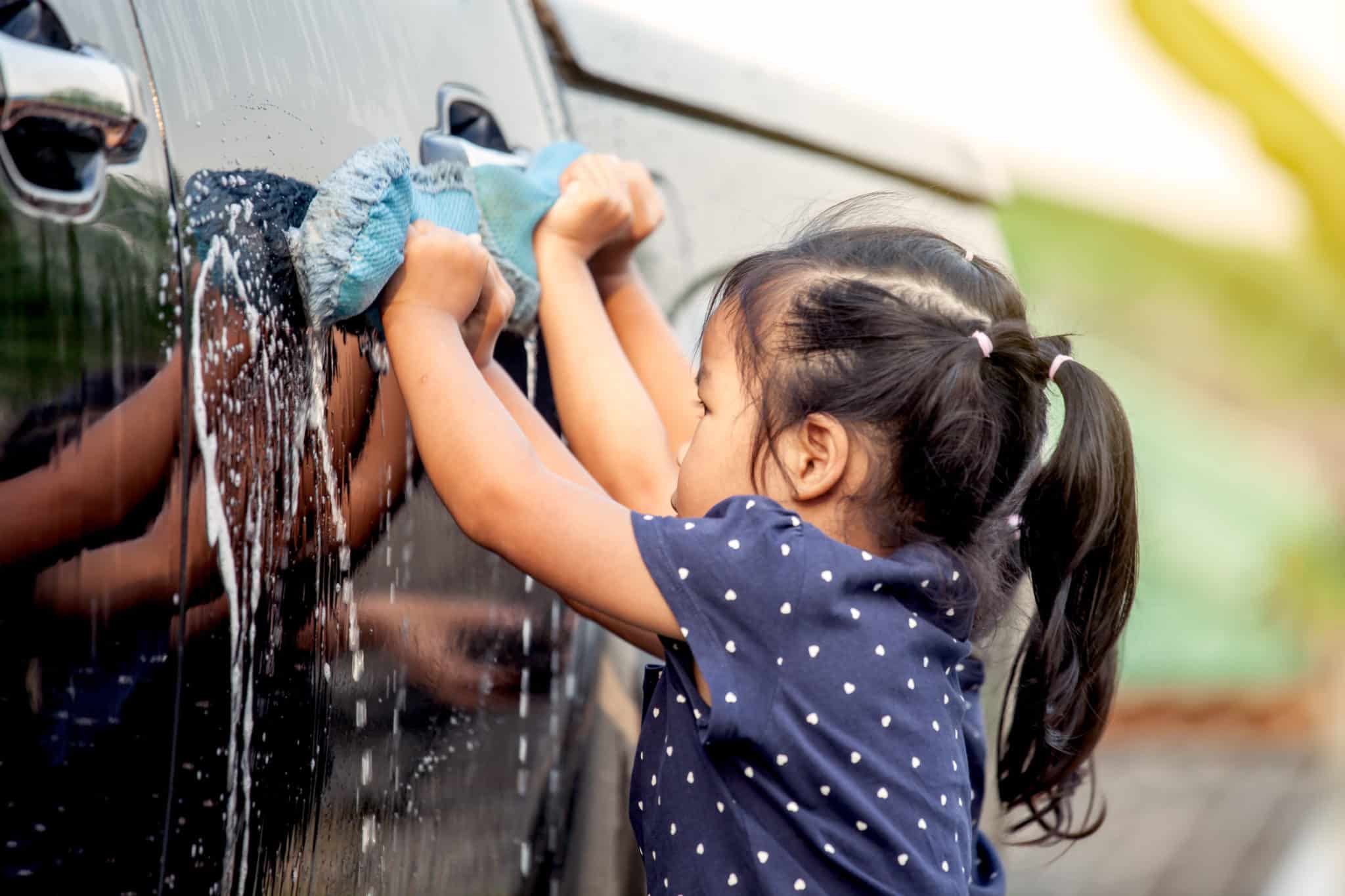 Little girl washing car during the summer