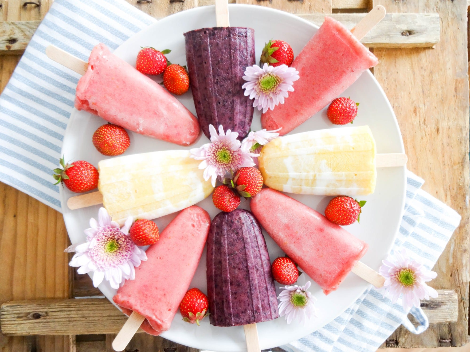 Homemade popsicles in different flavors and colors on white plate