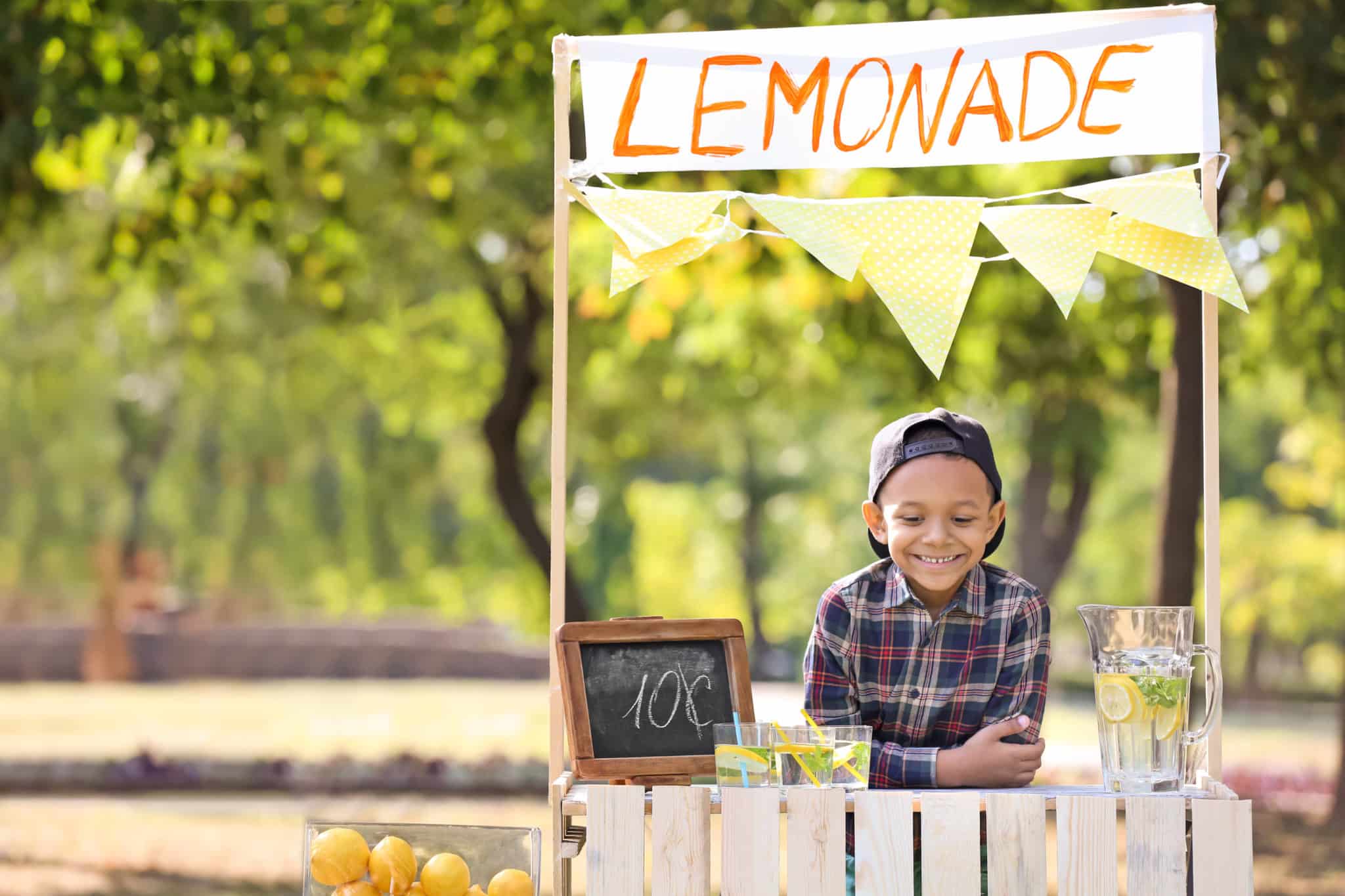 Little boy standing behind a lemonade stand during summer