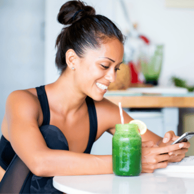 woman before workout having green smoothy snack on phone