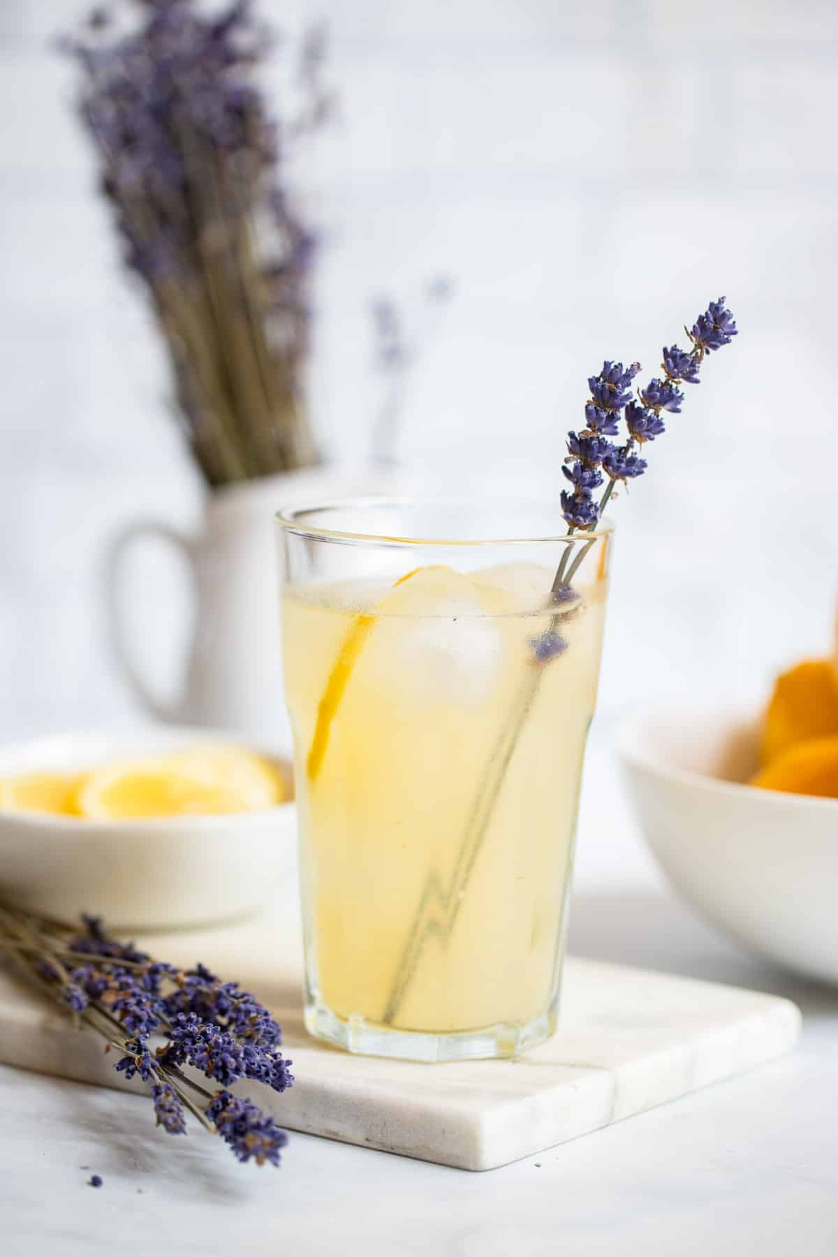 glass lavender lemonade with ice garnished with lemon slice and sprig of fresh lavender.