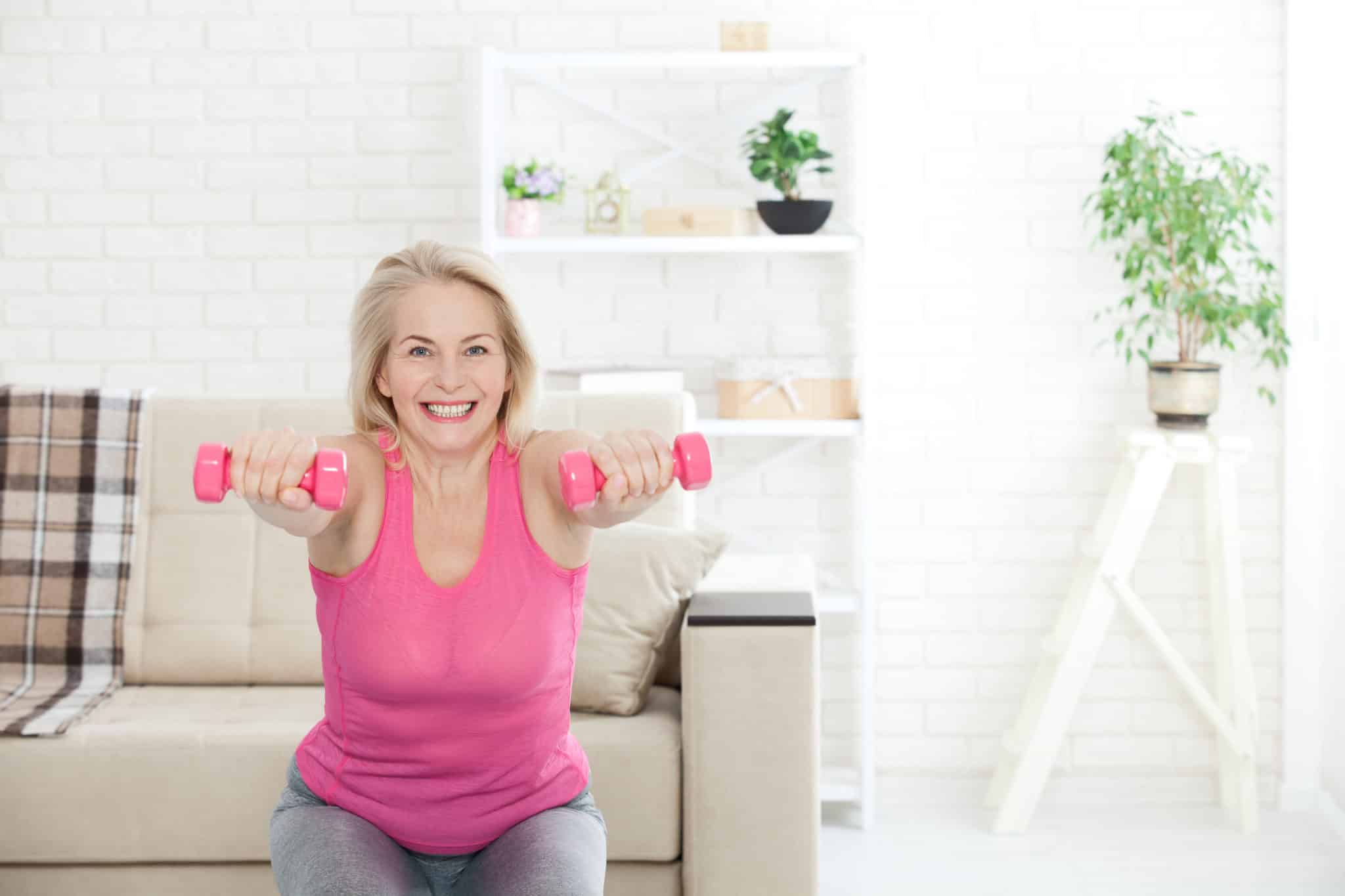 Middle aged woman squating with dumbbells in living room
