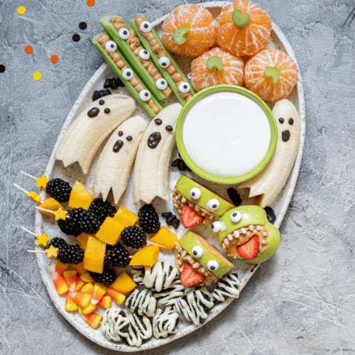 A large plate of healthy halloween recipes like banana ghosts, pumpkin clementines, celery fingers and apple monsters