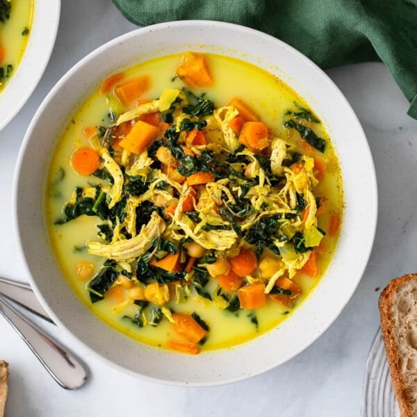 overhead shot of golden turmeric chicken soup serving in white bowl