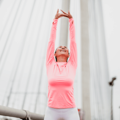 woman stretching to the sky on a bridge