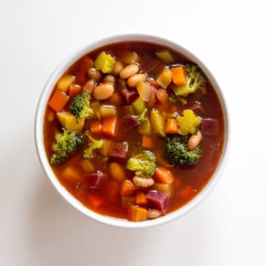 Bowl of detox vegetable soup on white background