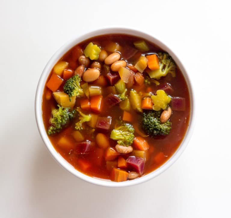 Bowl of detox vegetable soup on white background