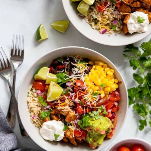 chipotle chicken burrito bowl topped with guacamole and cheese.