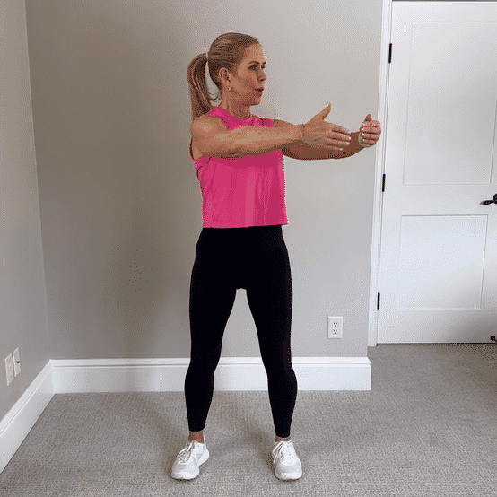 Chris Freytag wearing a pink tank top and black leggings performing pilates standing ab twists. 