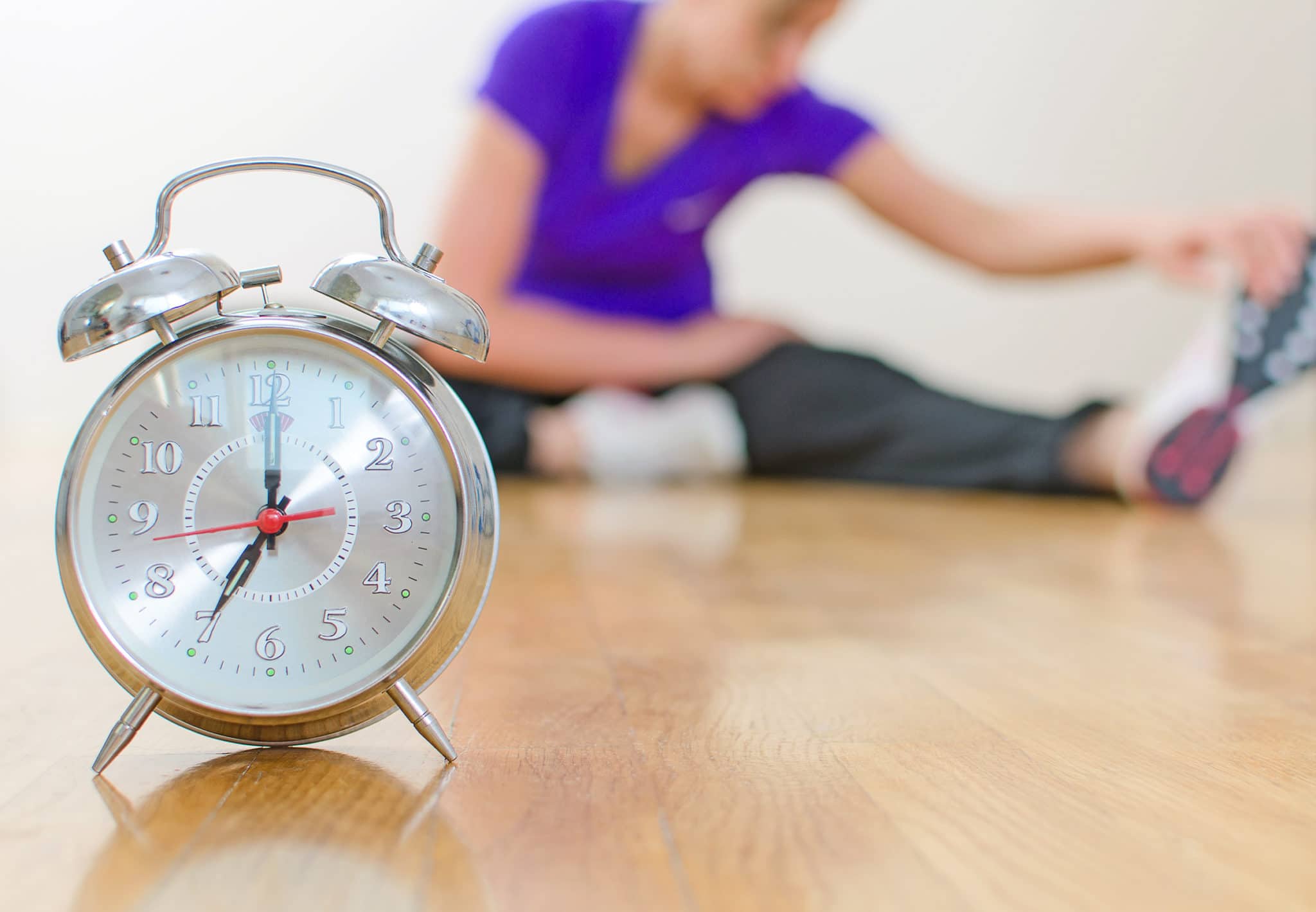 Woman stretching at home with clock in the forefront
