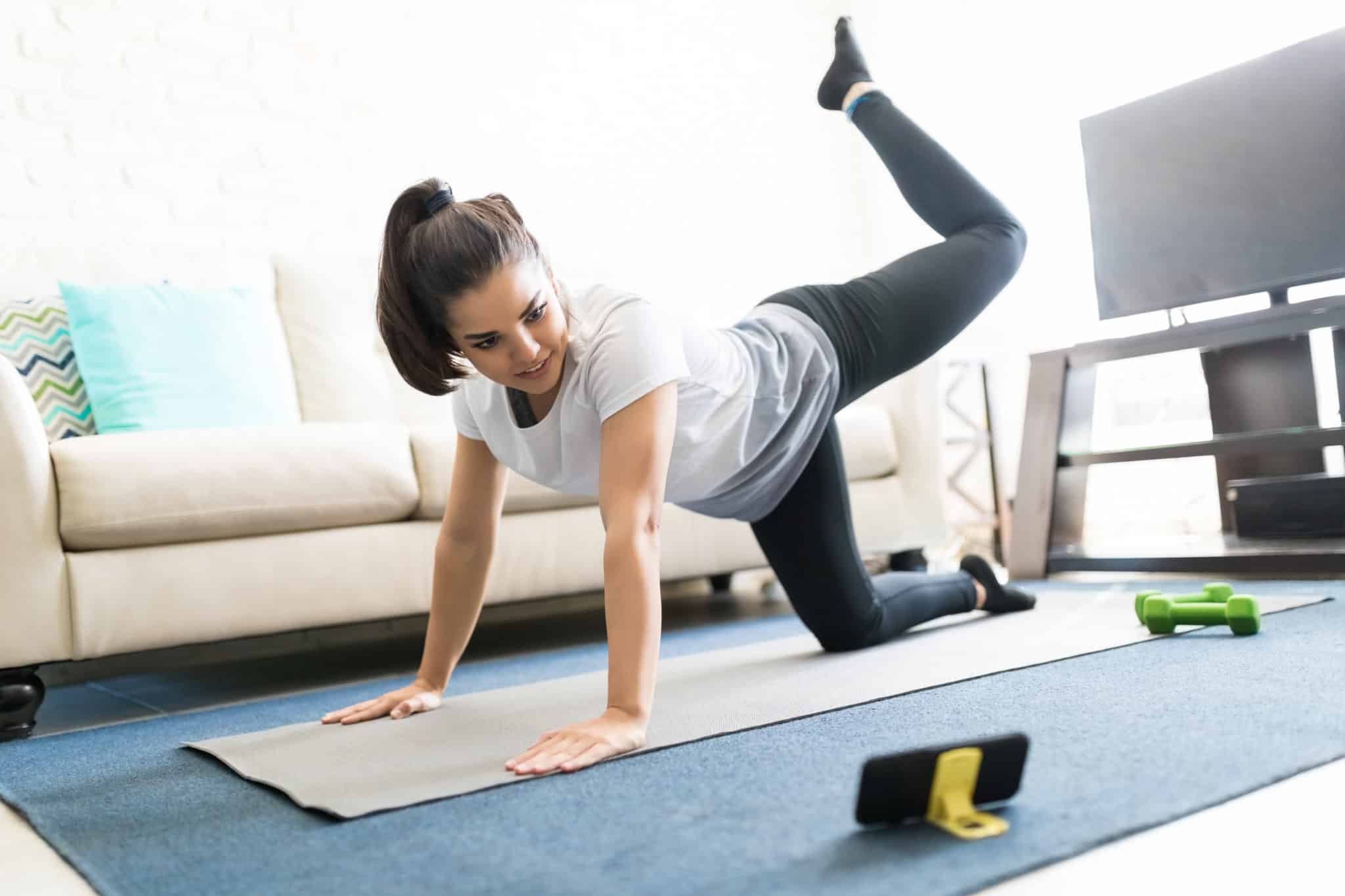 Woman doing an EMOM workout in living room looking at the phone timer