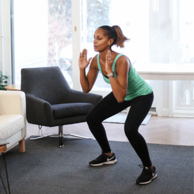 Young woman performing a squat in her living room