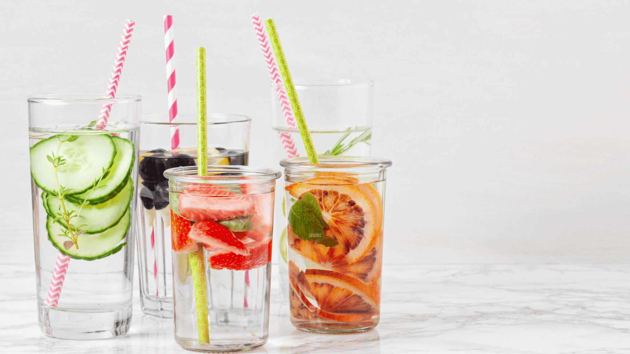 cups with straws filled with fruit and herbs