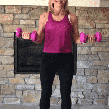 Chris Freytag wearing a pink tank top holding a halfway bicep curl with 12 lb dumbbell weights.