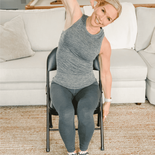 Chris Freytag seated on a black folding chair doing a seated side bend.