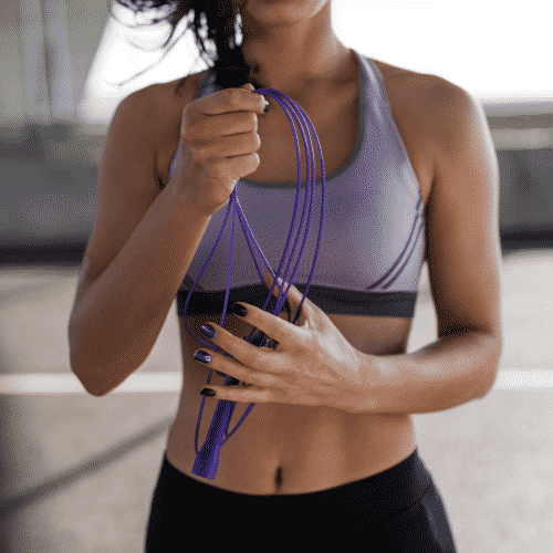 woman in purple workout shirt holding jump rope