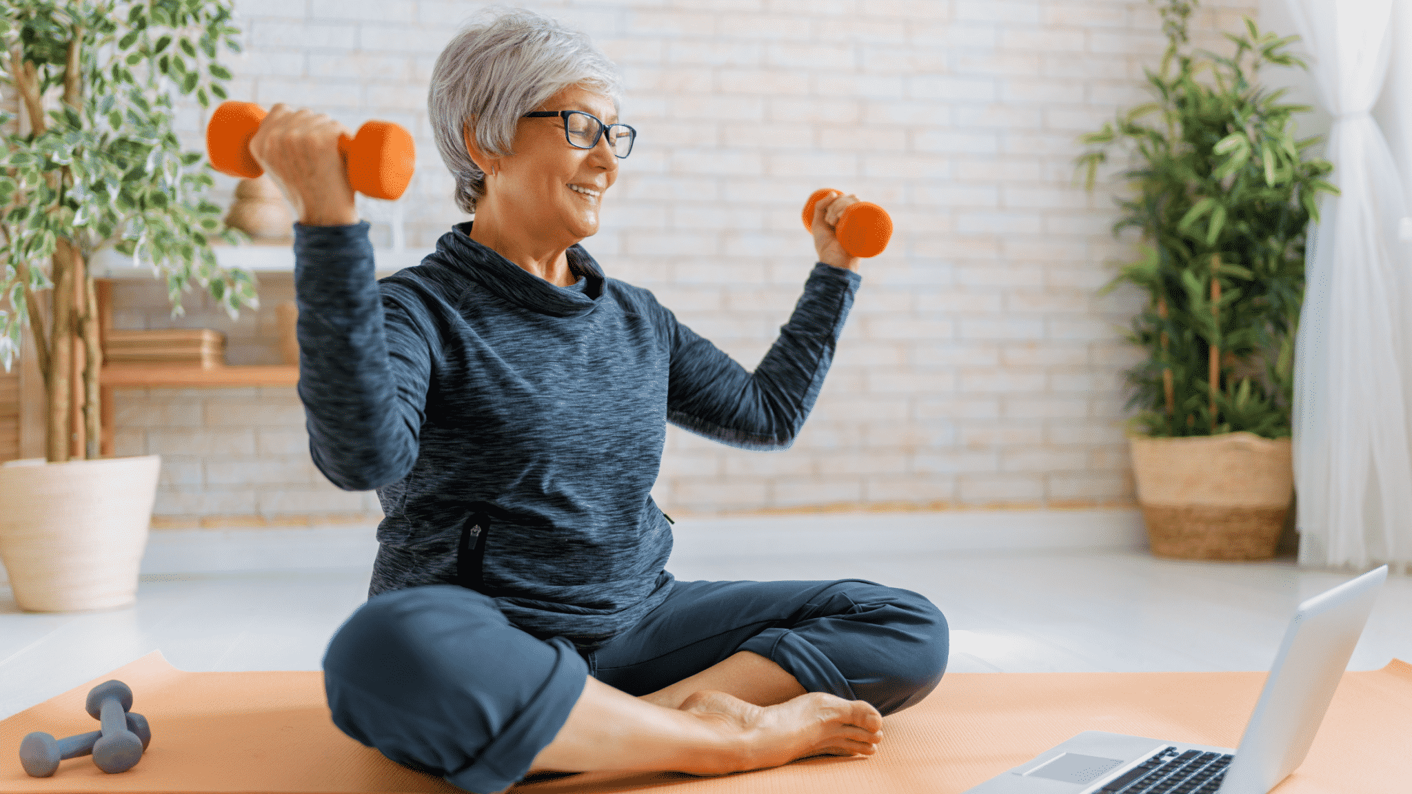 senior woman sitting on yoga mat with weights