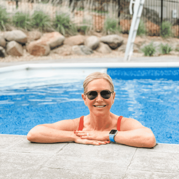 Chris Freytag poolside with sunglasses and a red bikini on.