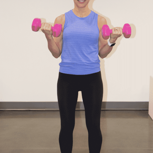 Chris Freytag holding a pair of pink dumbbells in a halfway bicep curl.