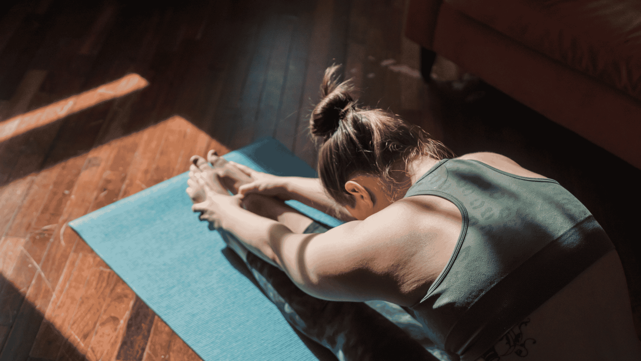 woman stretching forward on yoga matt