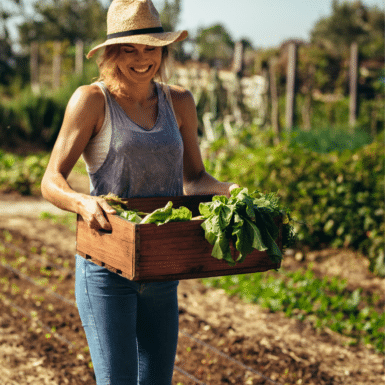 woman holding box of green veggies