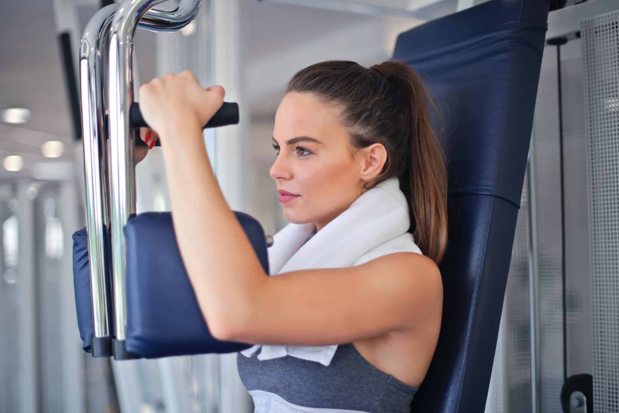 woman using weight machine for strength training at gym