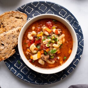 top view of single serving of hamburgers soup on white counter with bread