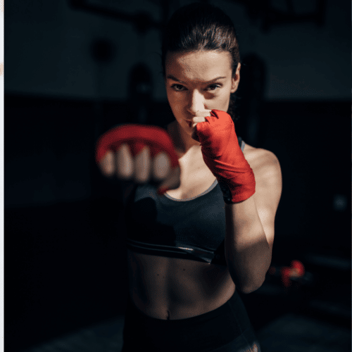 woman with red kickboxing gloves and black workout outfit