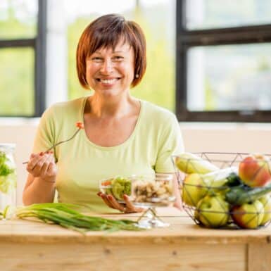 woman smiling eating best foods that lower cholesterol naturally