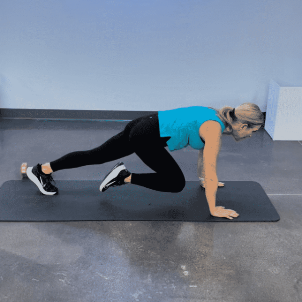 Chris Freytag wearing black leggings and a blue top doing a mountain climber