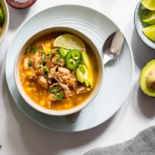 Top view of white chicken chili serving in white bowl on white countertop