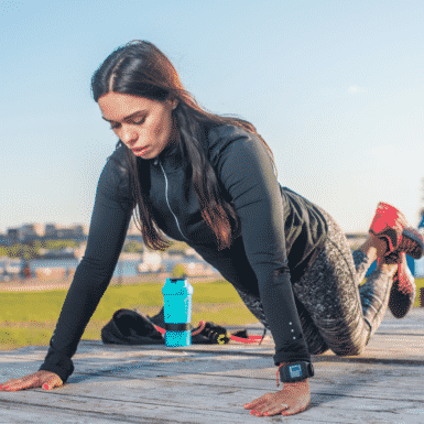 woman in black workout clothing doing a modified push up on her knees