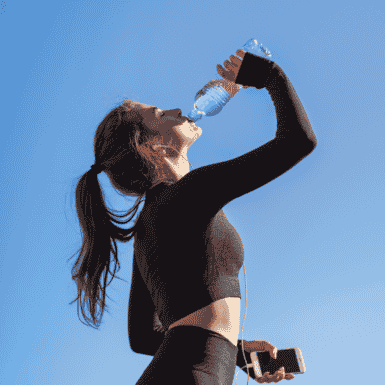 woman drinking water after workout on hot day