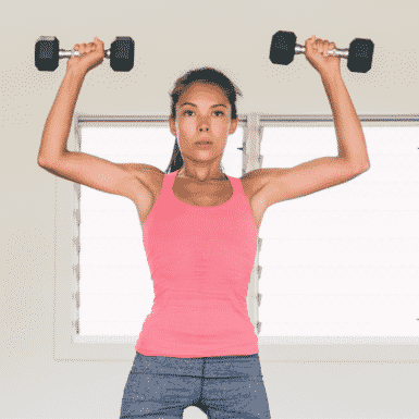 Young woman in pink shirt performing a standing dumbbell Arnold press