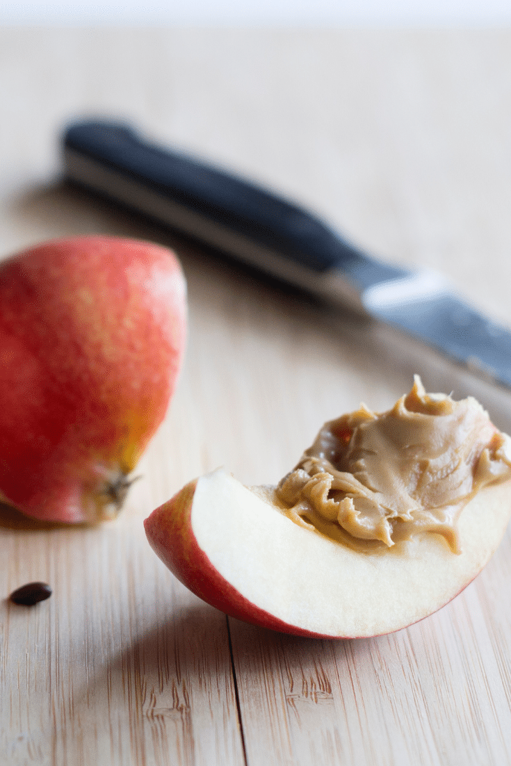 An apple slice with almond butter and a knife