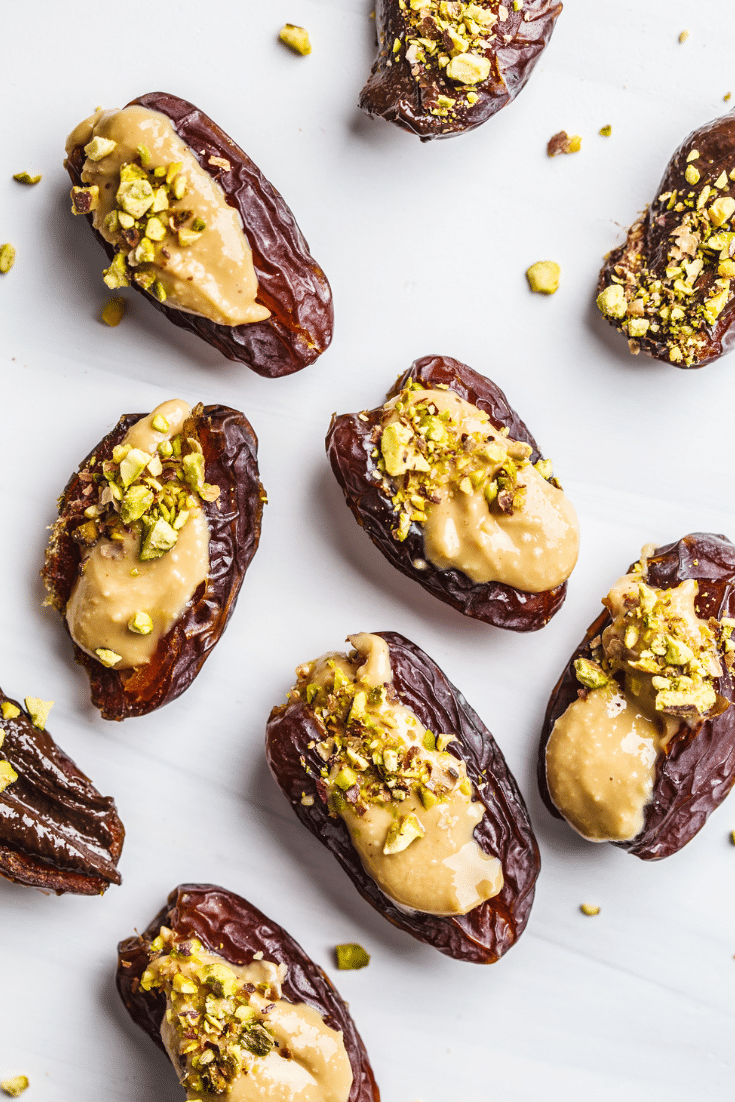 Nut butter stuffed dates with pistachios on a white background