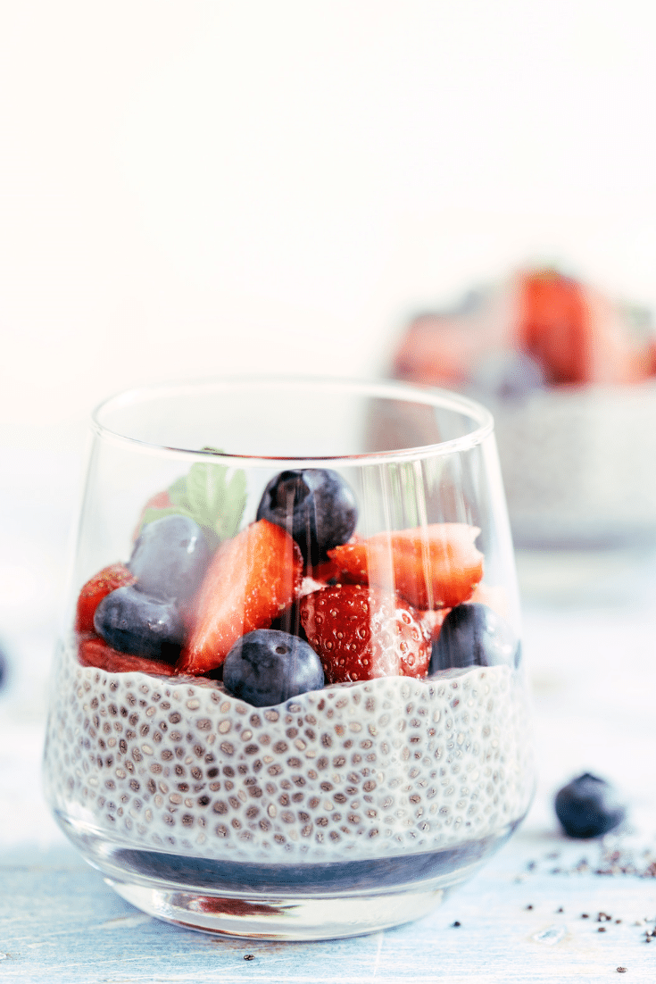Glass cup with yogurt chia pudding topped with fresh berries