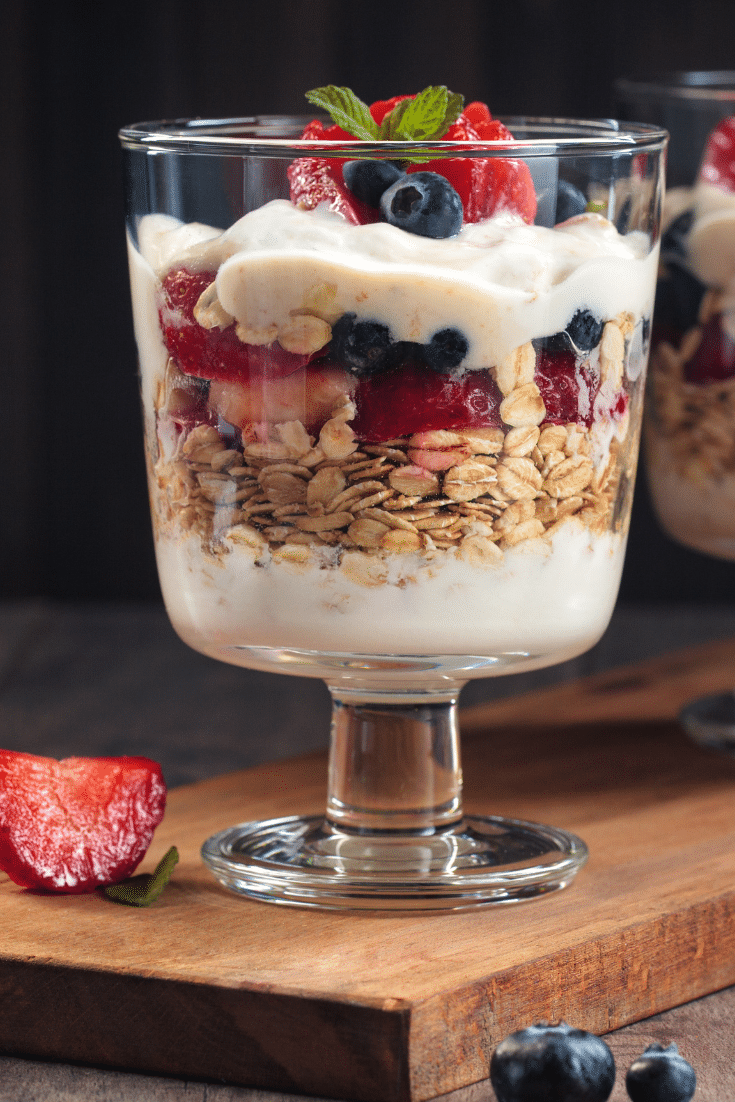 A yogurt parfait in a glass jar with granola and berries