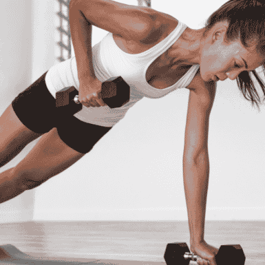 Young woman performing dumbbell renegade row on workout mat