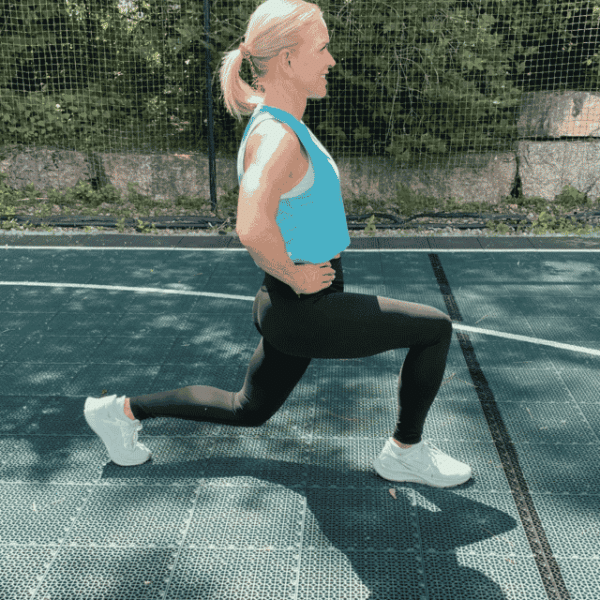 Chris Freytag wearing a blue tank top and black leggings holding a forward lunge.