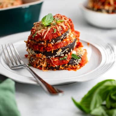 single serving of healthy eggplant parmesan on white plate with fork