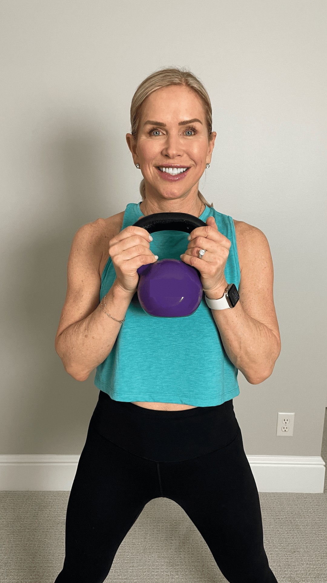 Chris Freytag wearing a teal tank top holding a purple vinyl coated kettlebell.