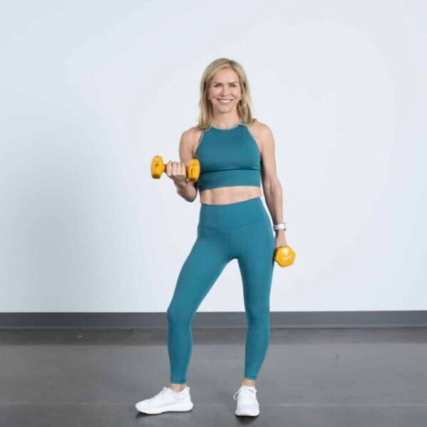 Chris Freytag wearing a blue matching outfit lifting orange dumbbells.