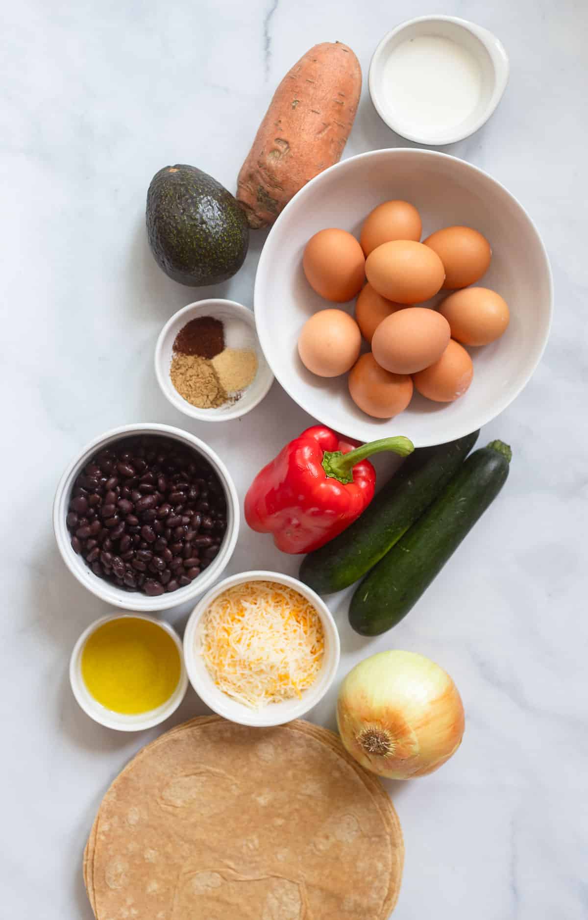 healthy breakfast burrito ingredients in white bowls on a white background.