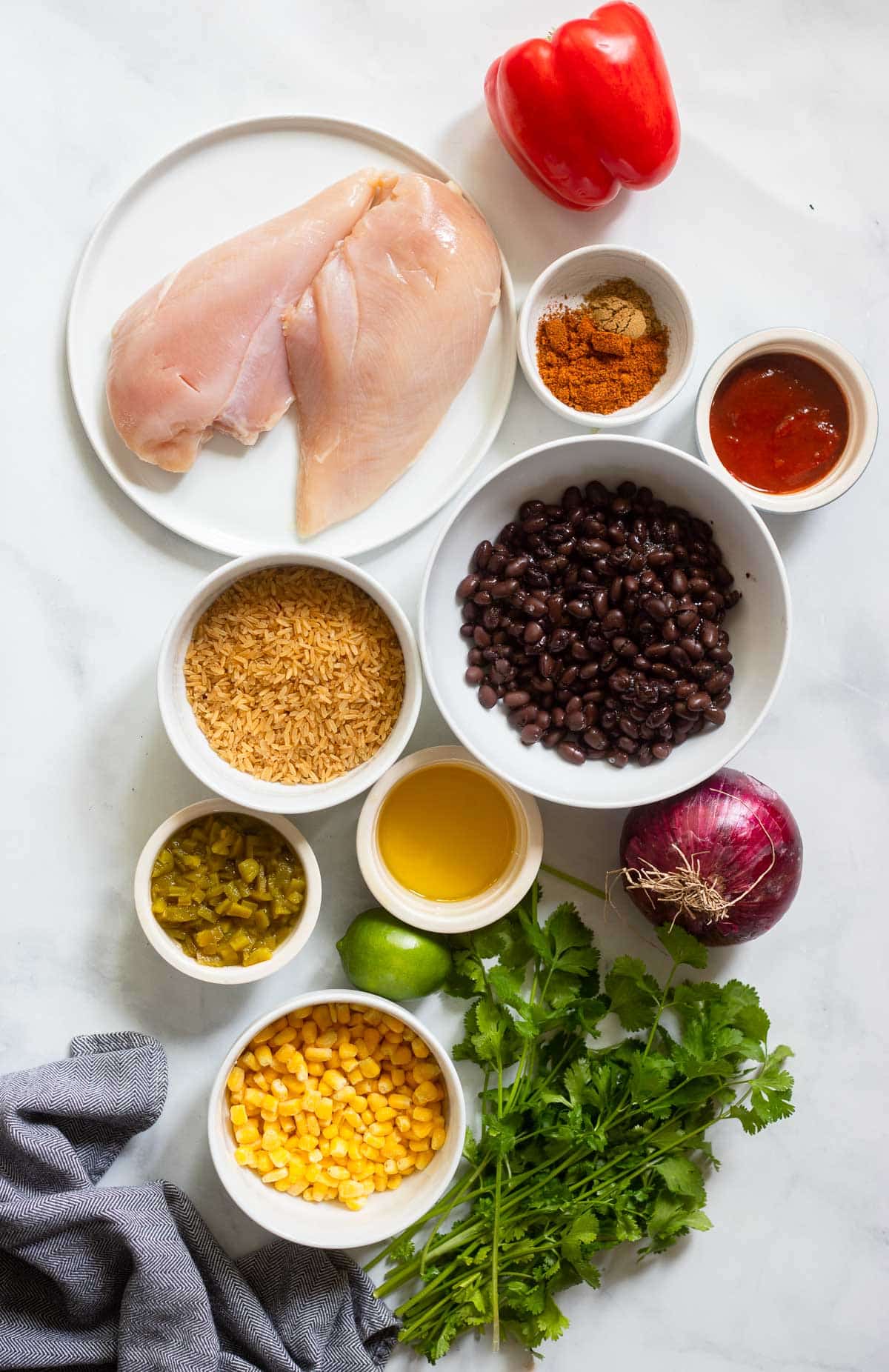 chipotle chicken bowl ingredients in white dishes on a white background.