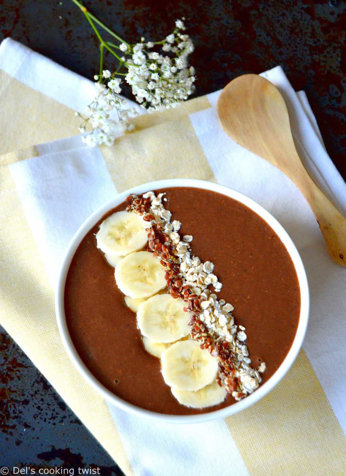 The brown carob powder smoothie bowl topped with bananas and seeds.